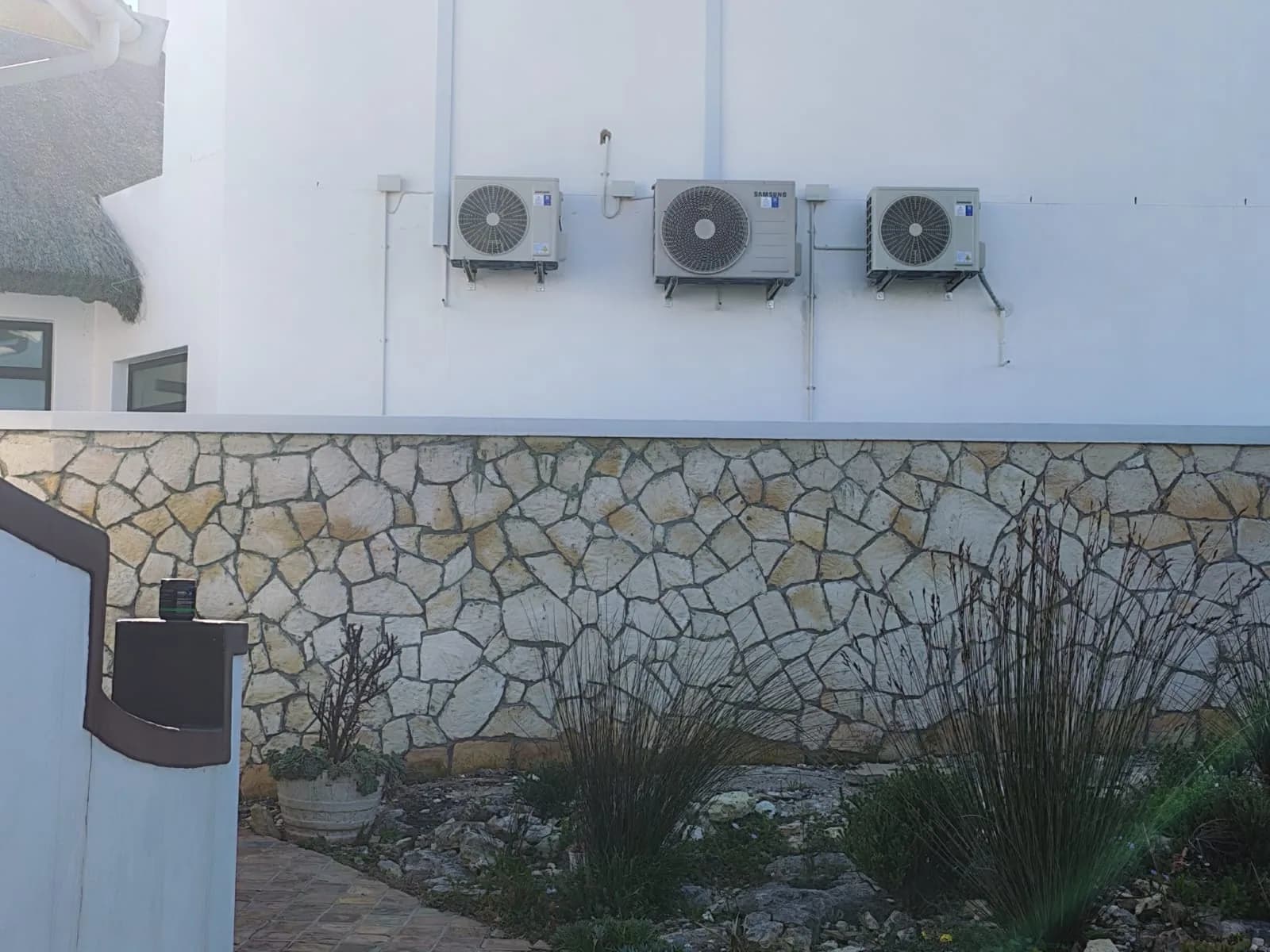 Three outdoor air-conditioning condenser units mounted in a row on an exterior wall.