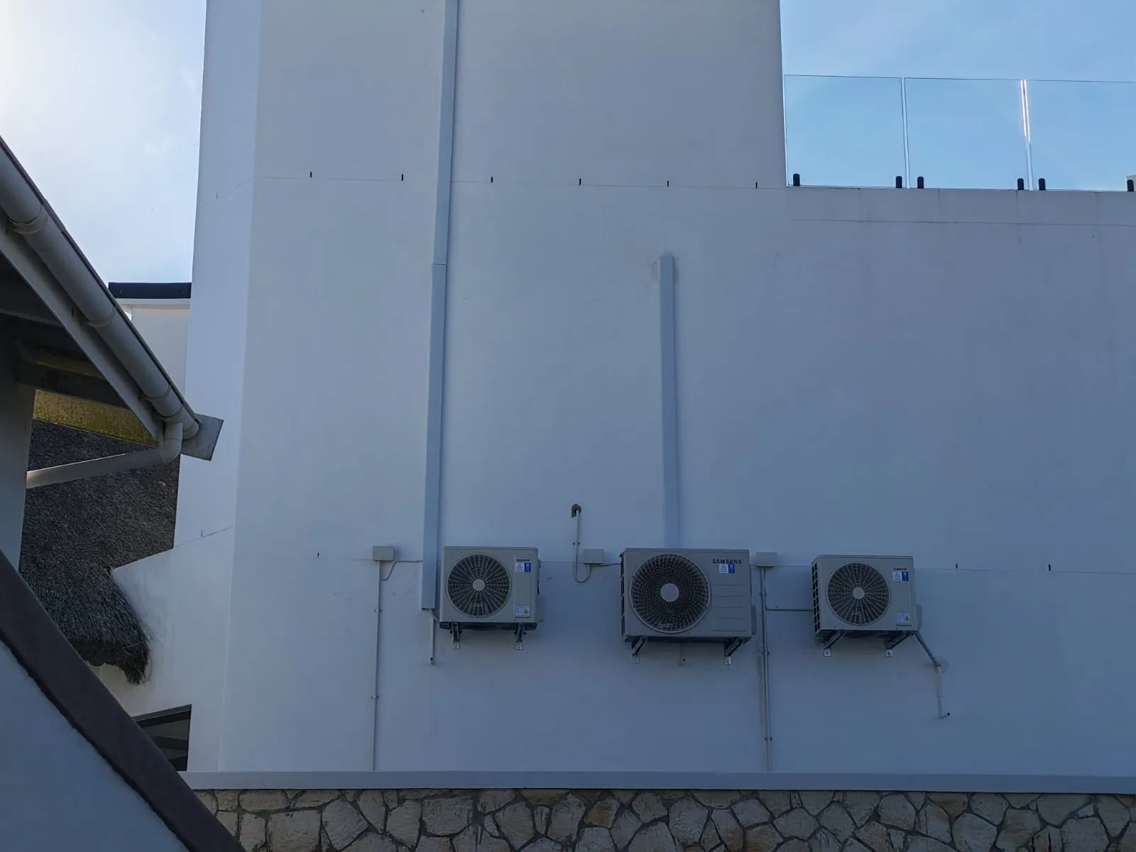 Exterior view of three air-conditioning condensers and their pipework.