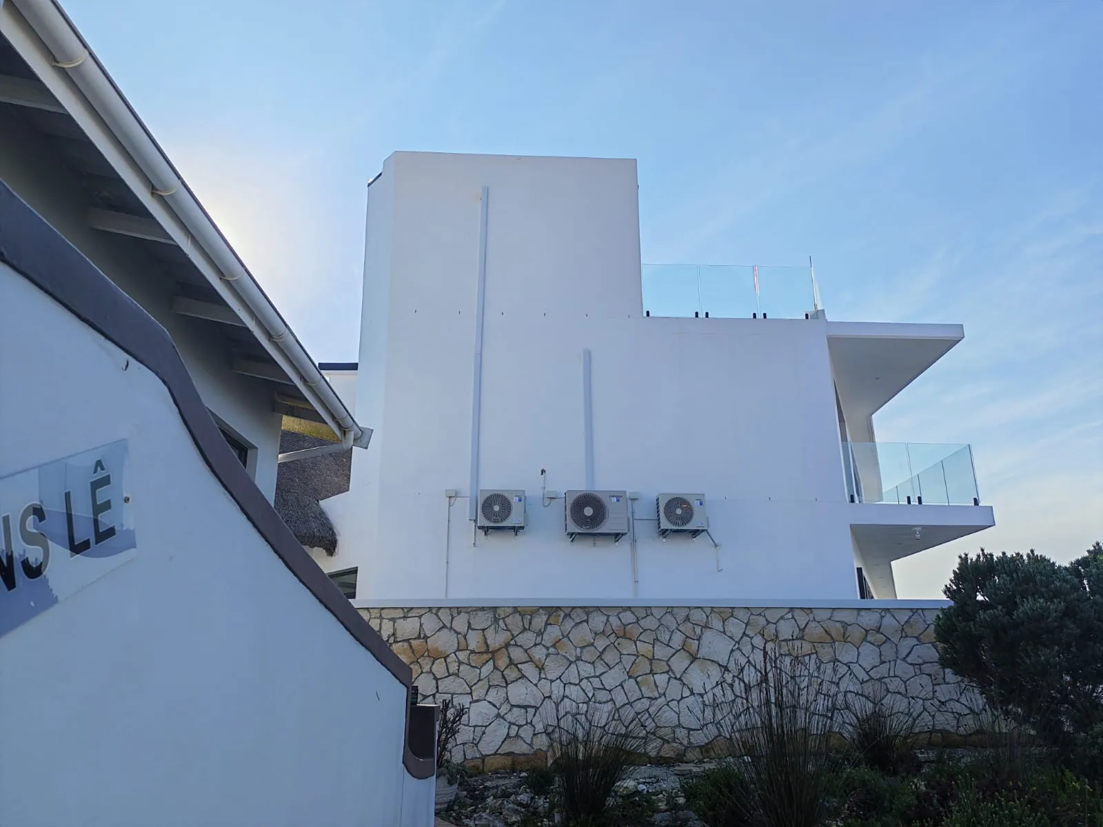 Wide exterior view of three wall-mounted air-conditioning condenser units.