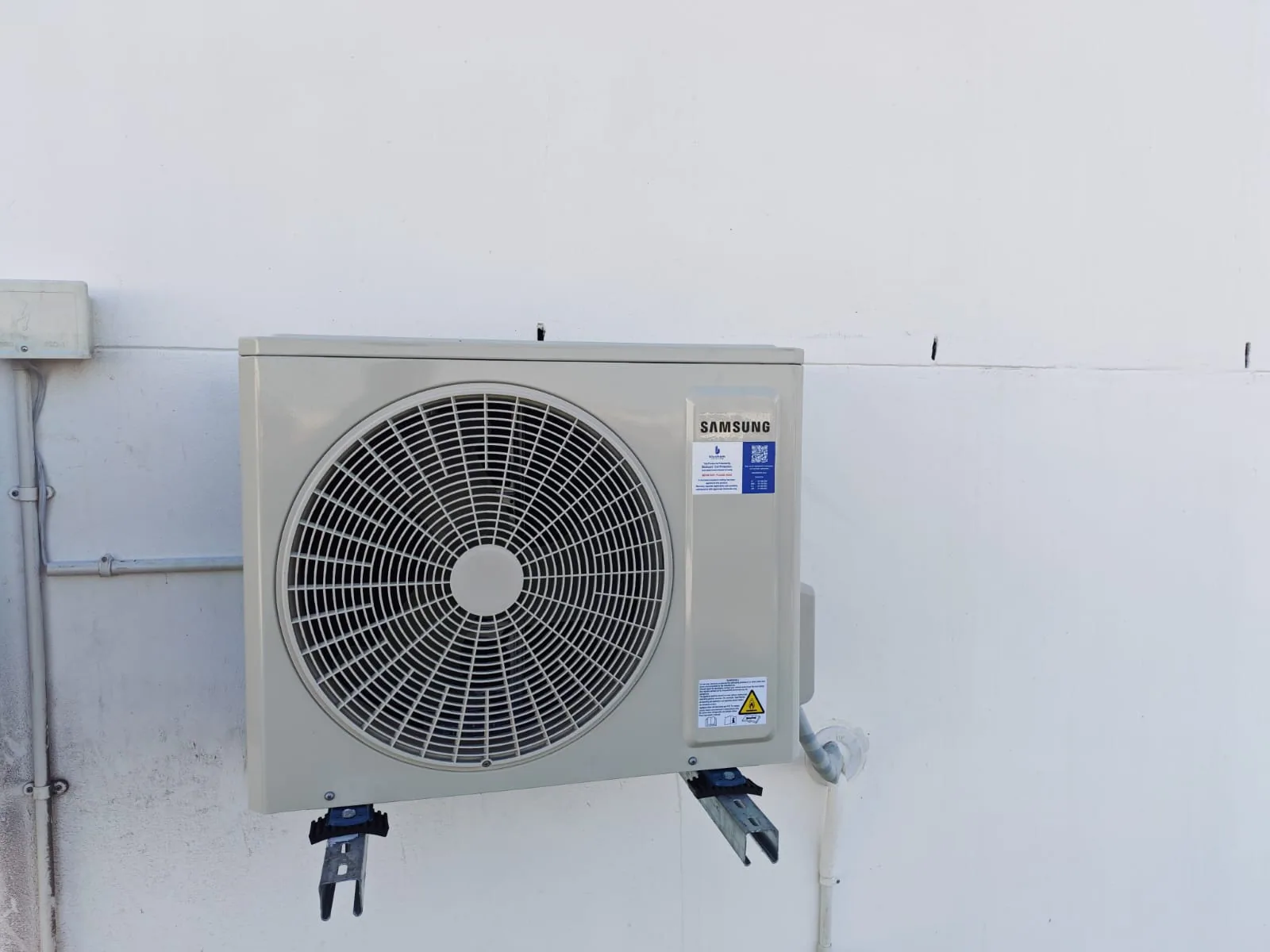 Close view of a Samsung outdoor air-conditioning condenser and mounting brackets.
