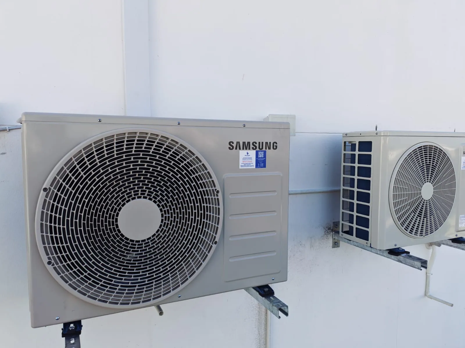 Outdoor air-conditioning condenser installed against a white exterior wall.