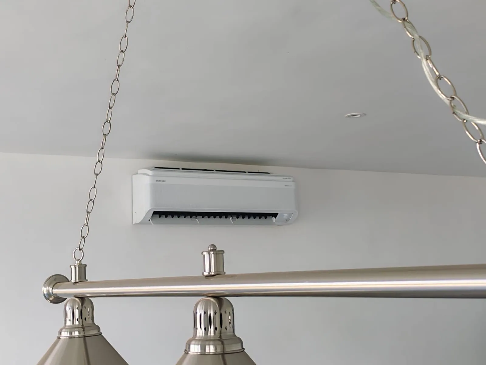 Indoor split air-conditioning unit installed above a hanging light fitting.