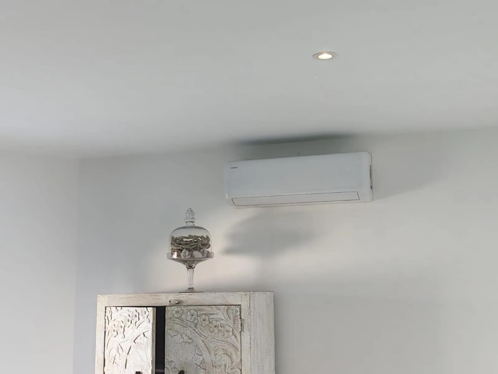 Air-conditioning unit installed above decorative shelving in a living space.