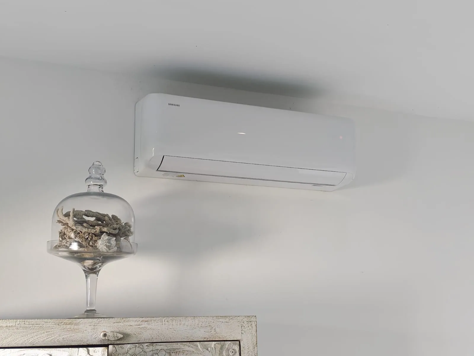 Wall-mounted air-conditioning unit above a mirror and interior display.
