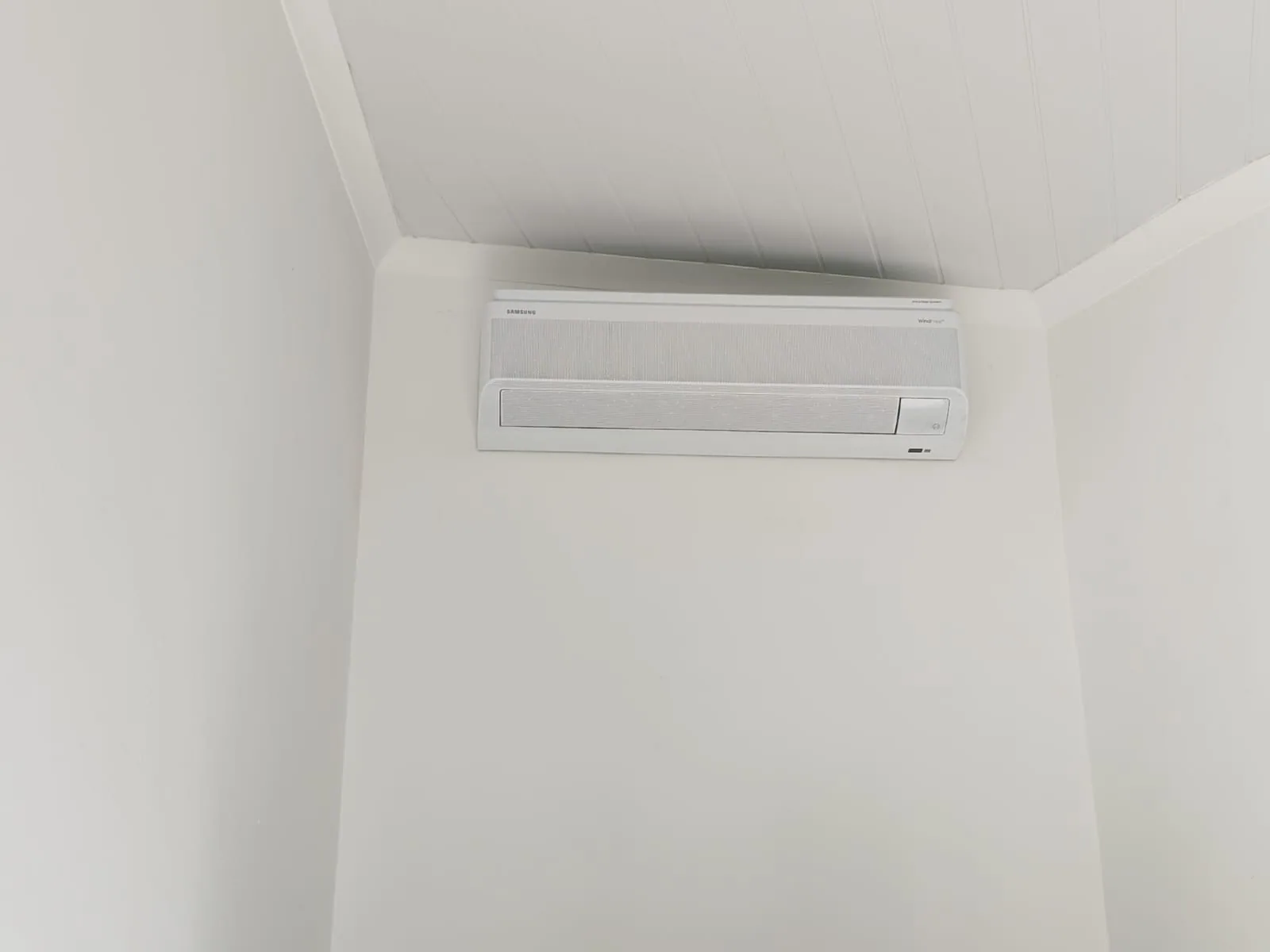 Split air-conditioning unit installed beneath a sloped interior ceiling.