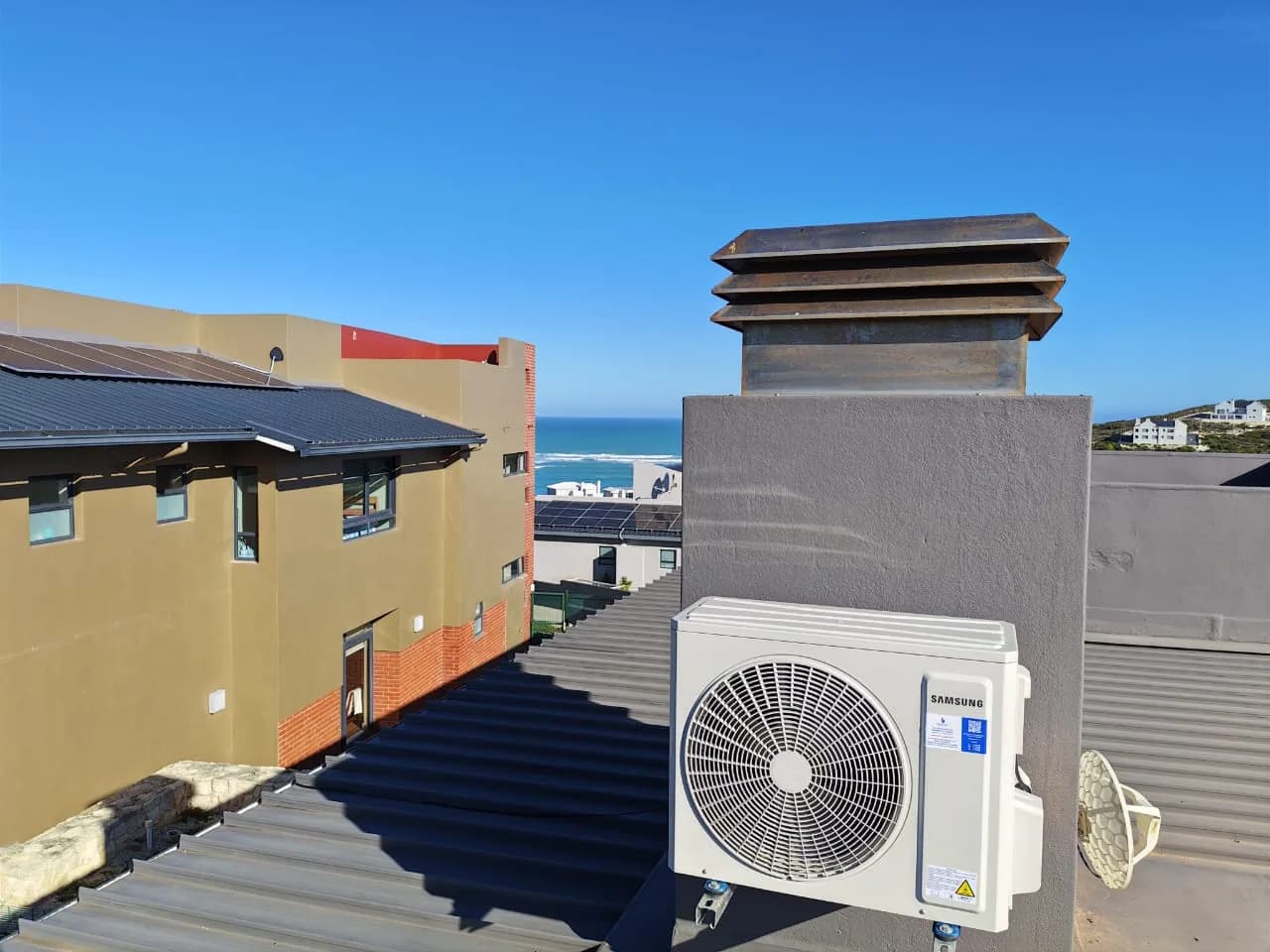 Outdoor air-conditioning condenser installed on a rooftop mounting bracket.