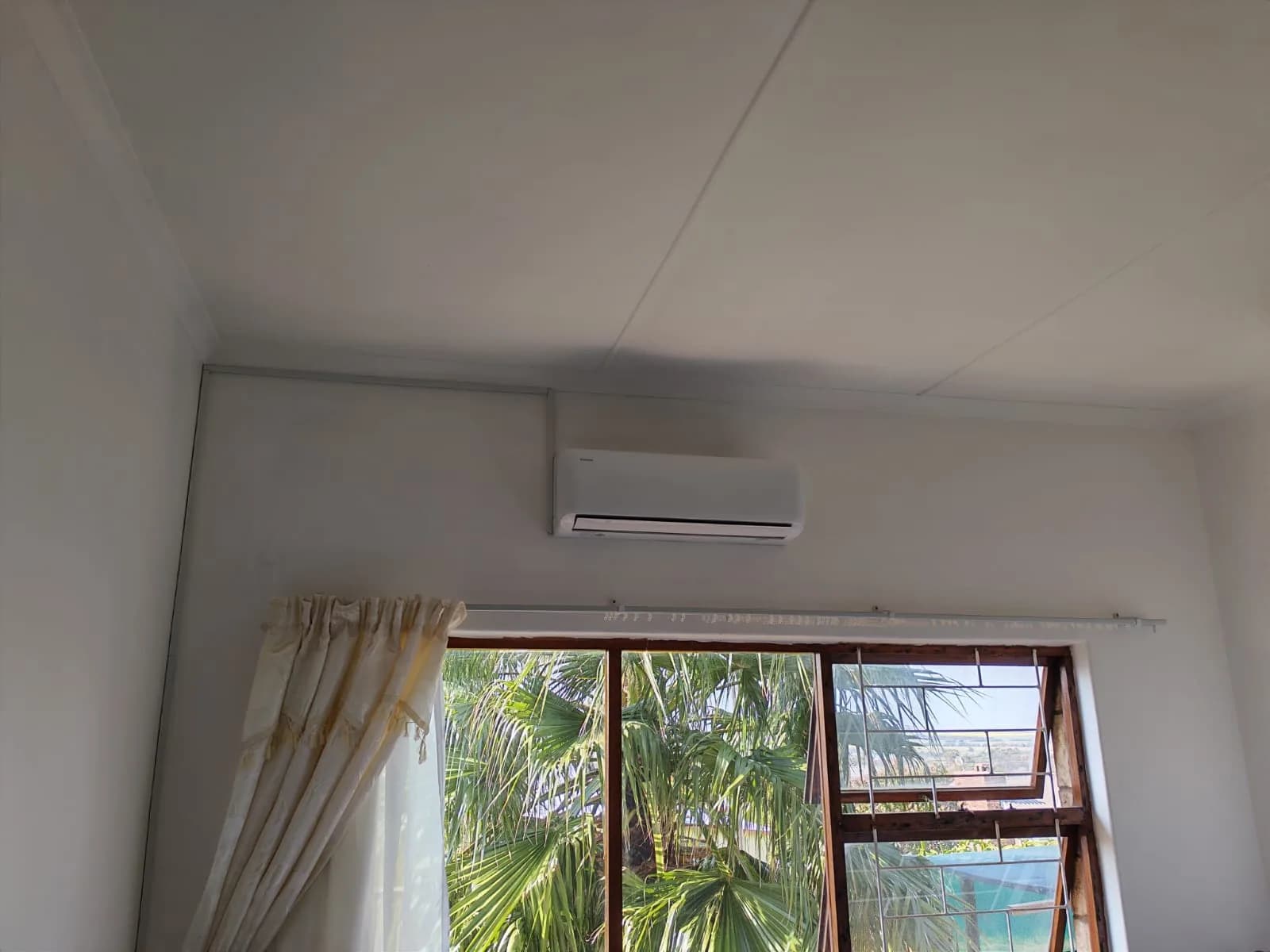 Indoor split air-conditioning unit installed above a large window.