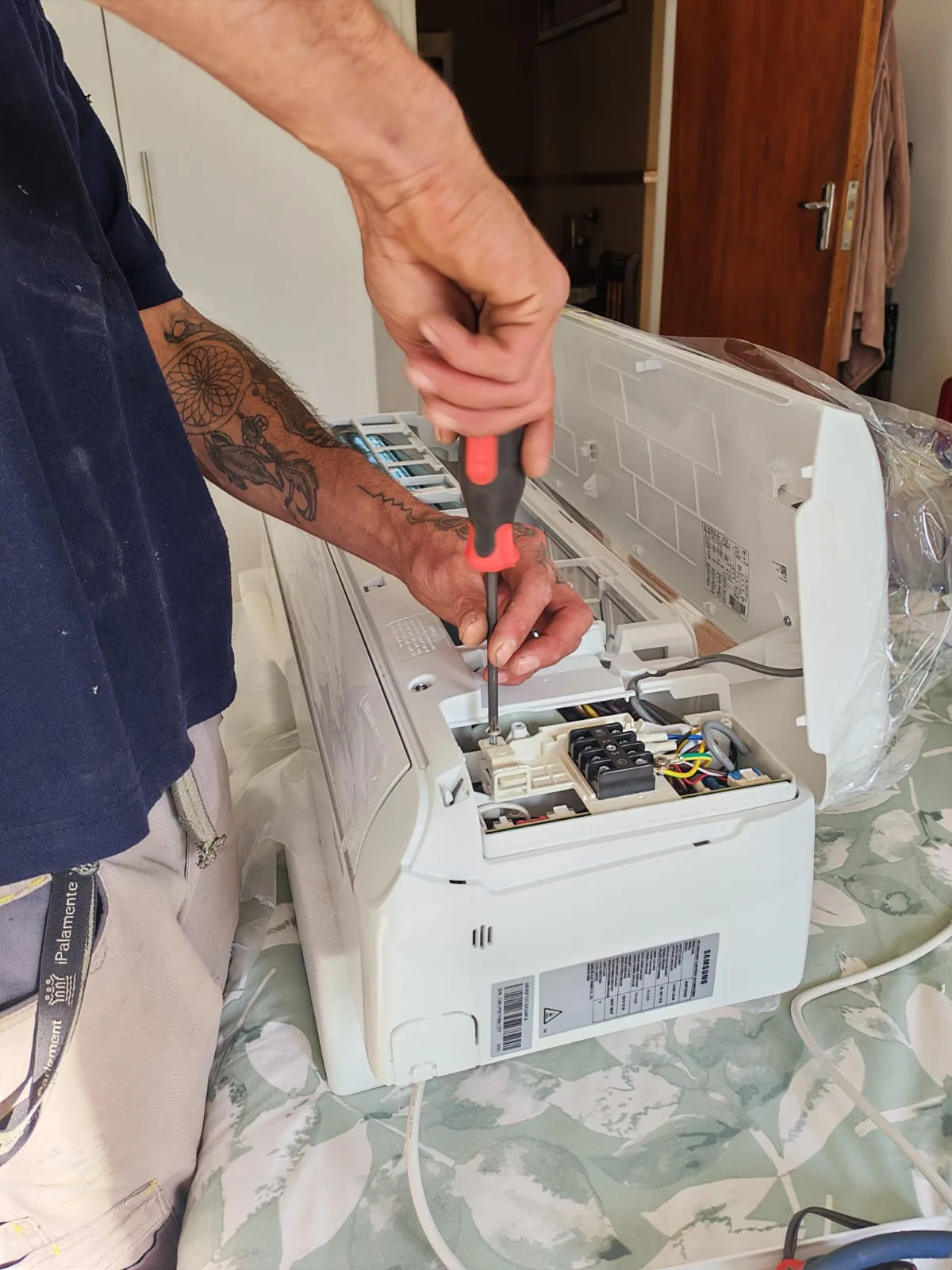 Technician working on the electrical connections of an indoor air-conditioning unit.