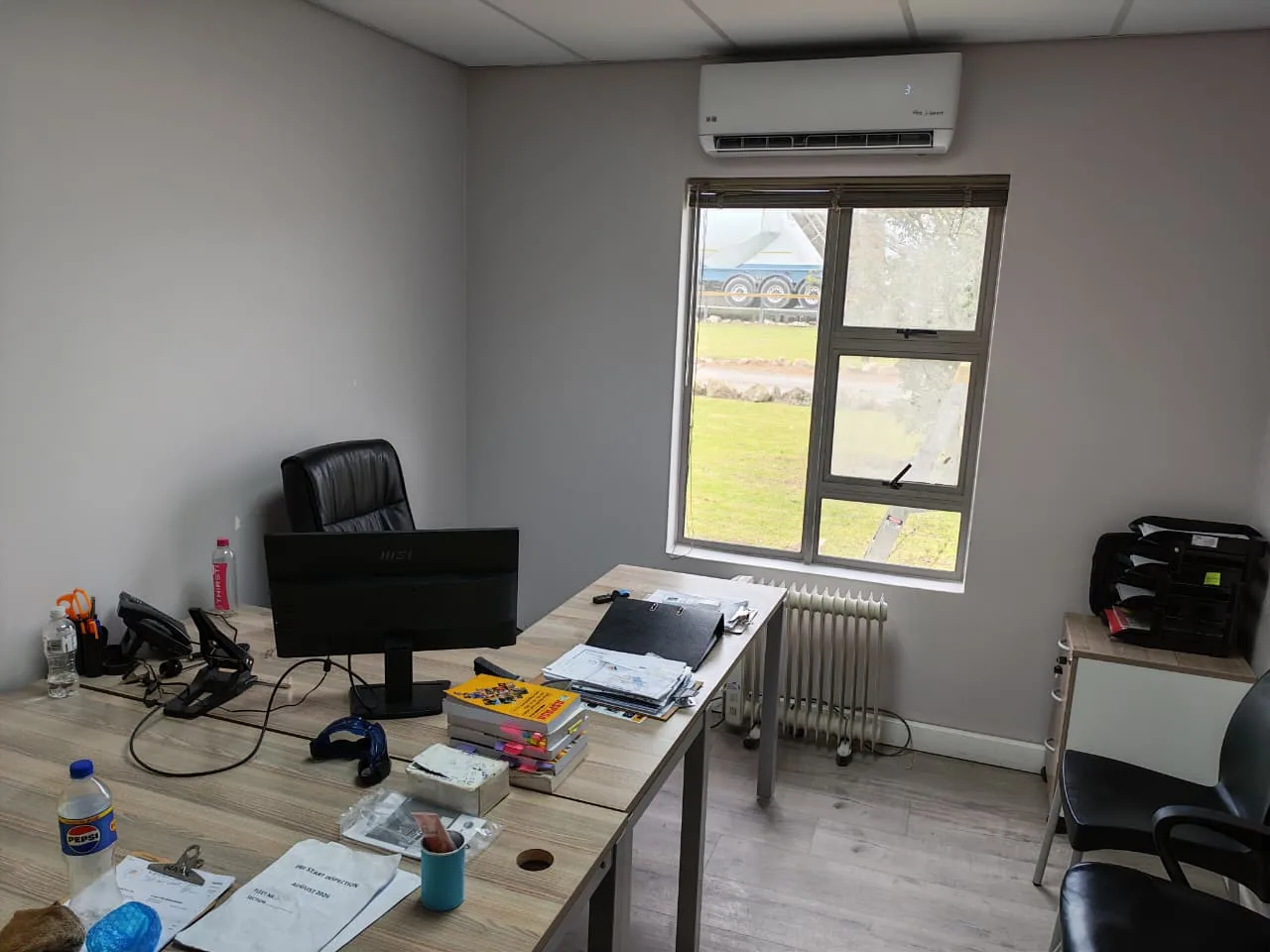 Wall-mounted split air-conditioning unit installed above a window in an office.