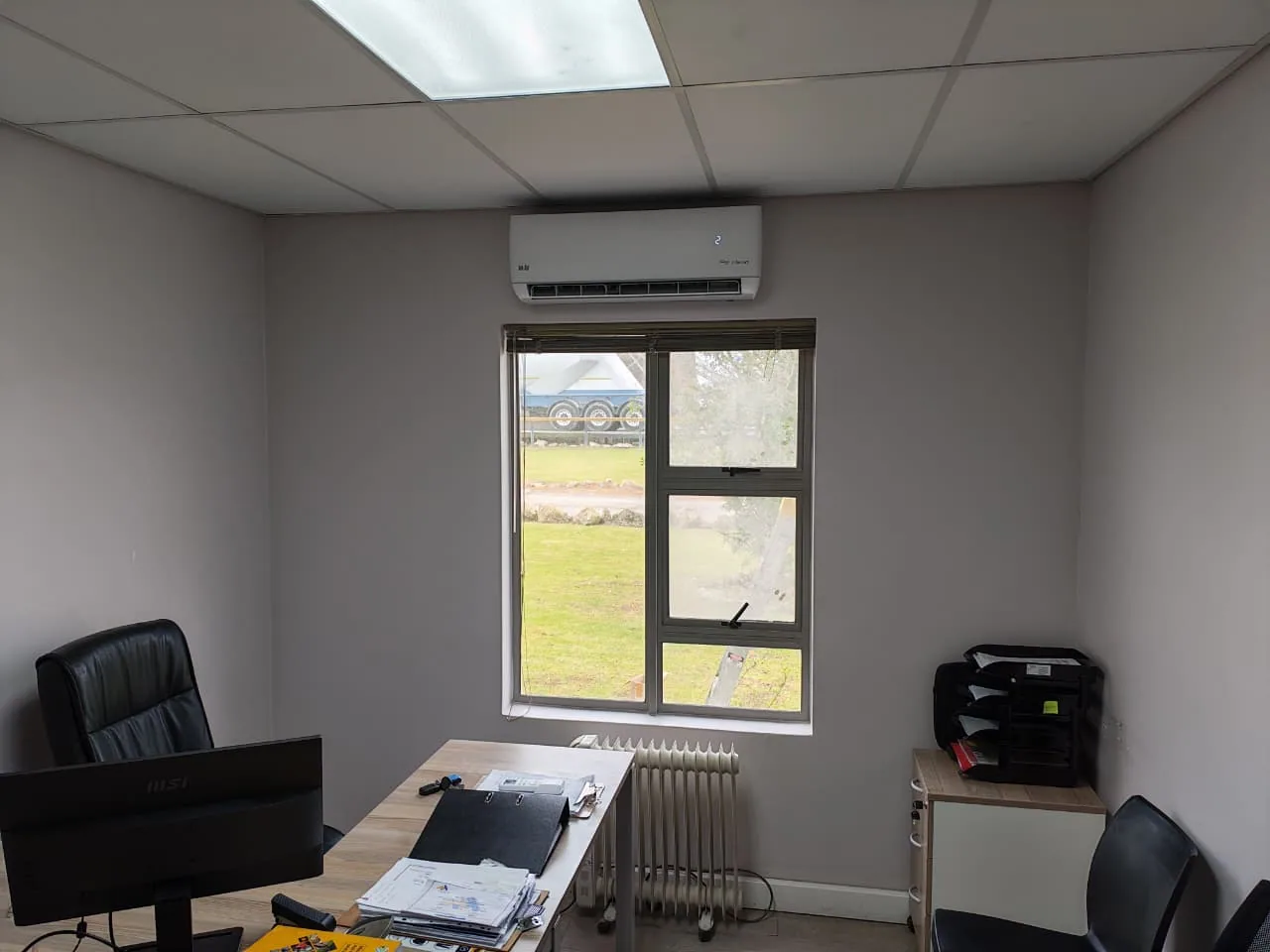 Front view of a wall-mounted split air-conditioning unit above an office window.